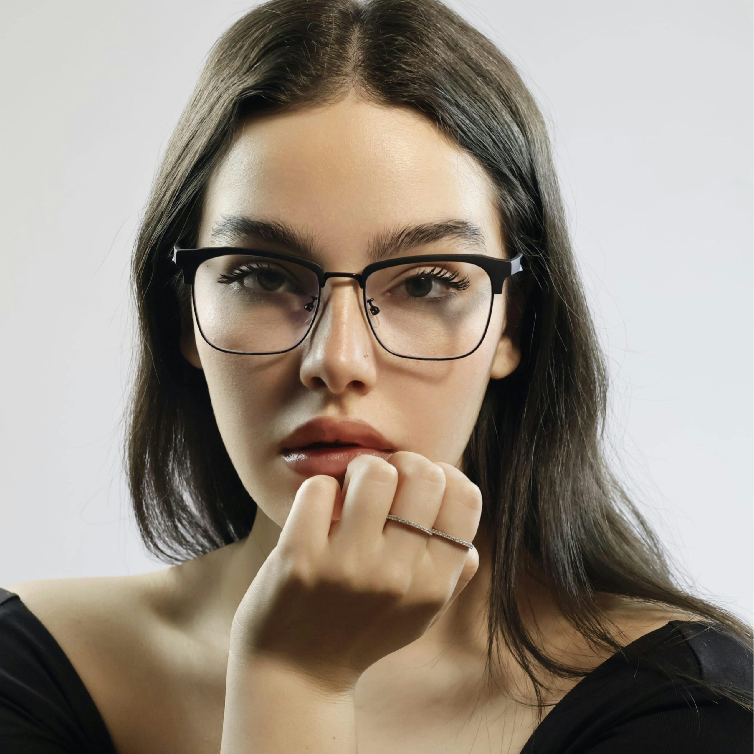 Close-up studio portrait of a young woman wearing stylish glasses, exuding elegance and sophistication.