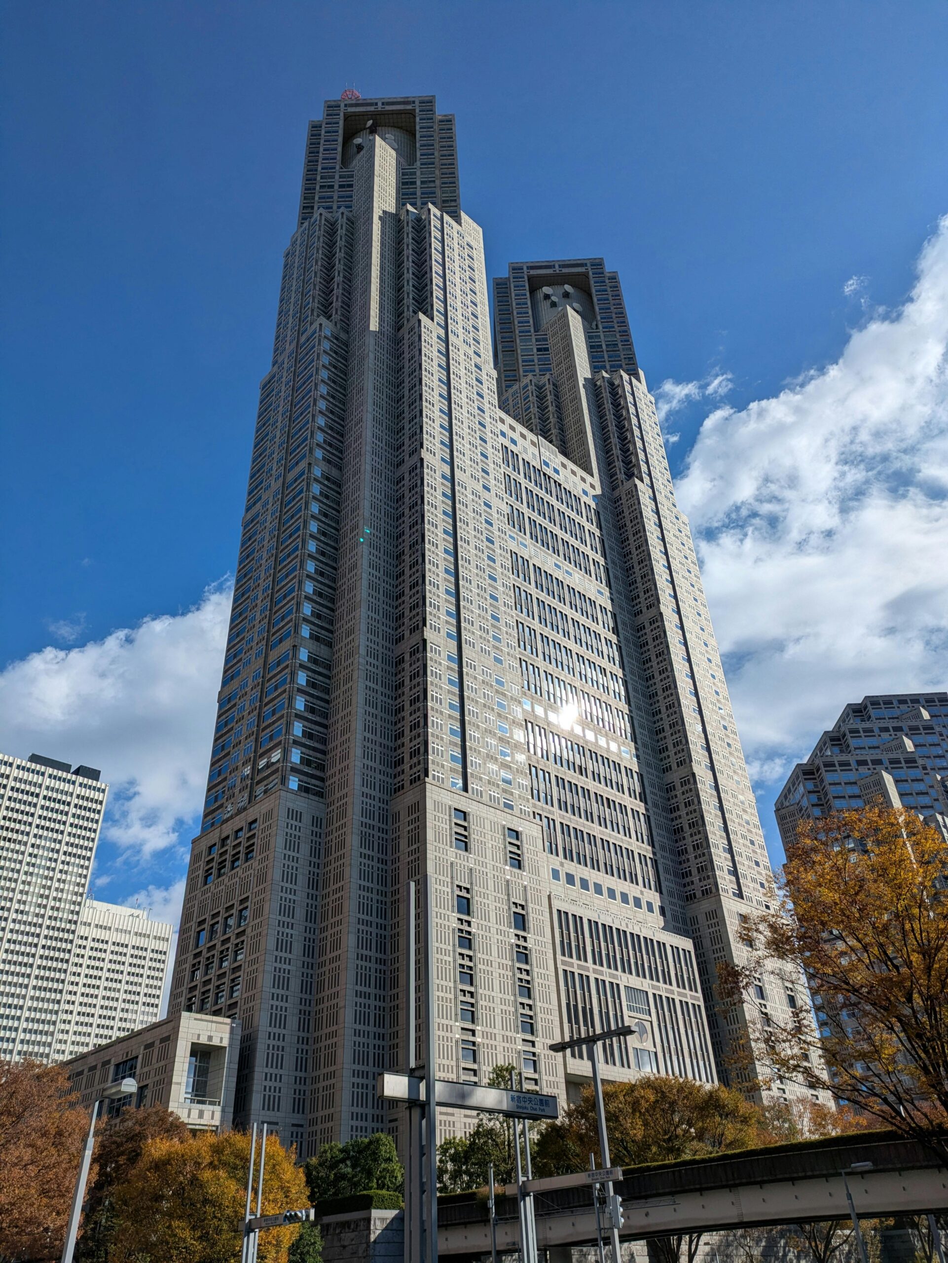 Majestic view of Tokyo Metropolitan Government Building against a bright blue sky with clouds.